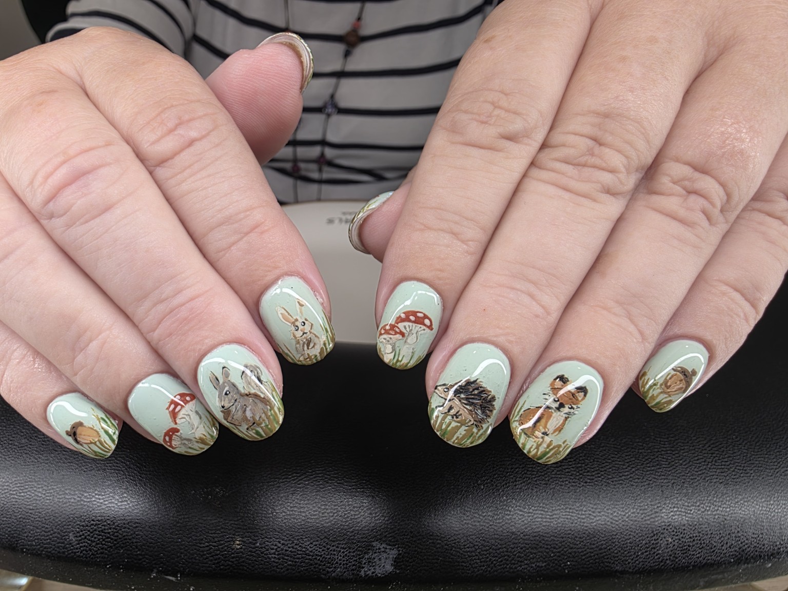 Detailed woodland nail art on a pale green manicure